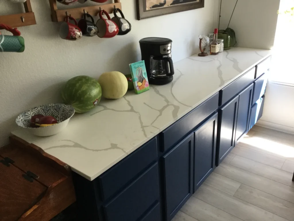 Calacatta-style white quartz with bold gray veining on navy blue cabinets