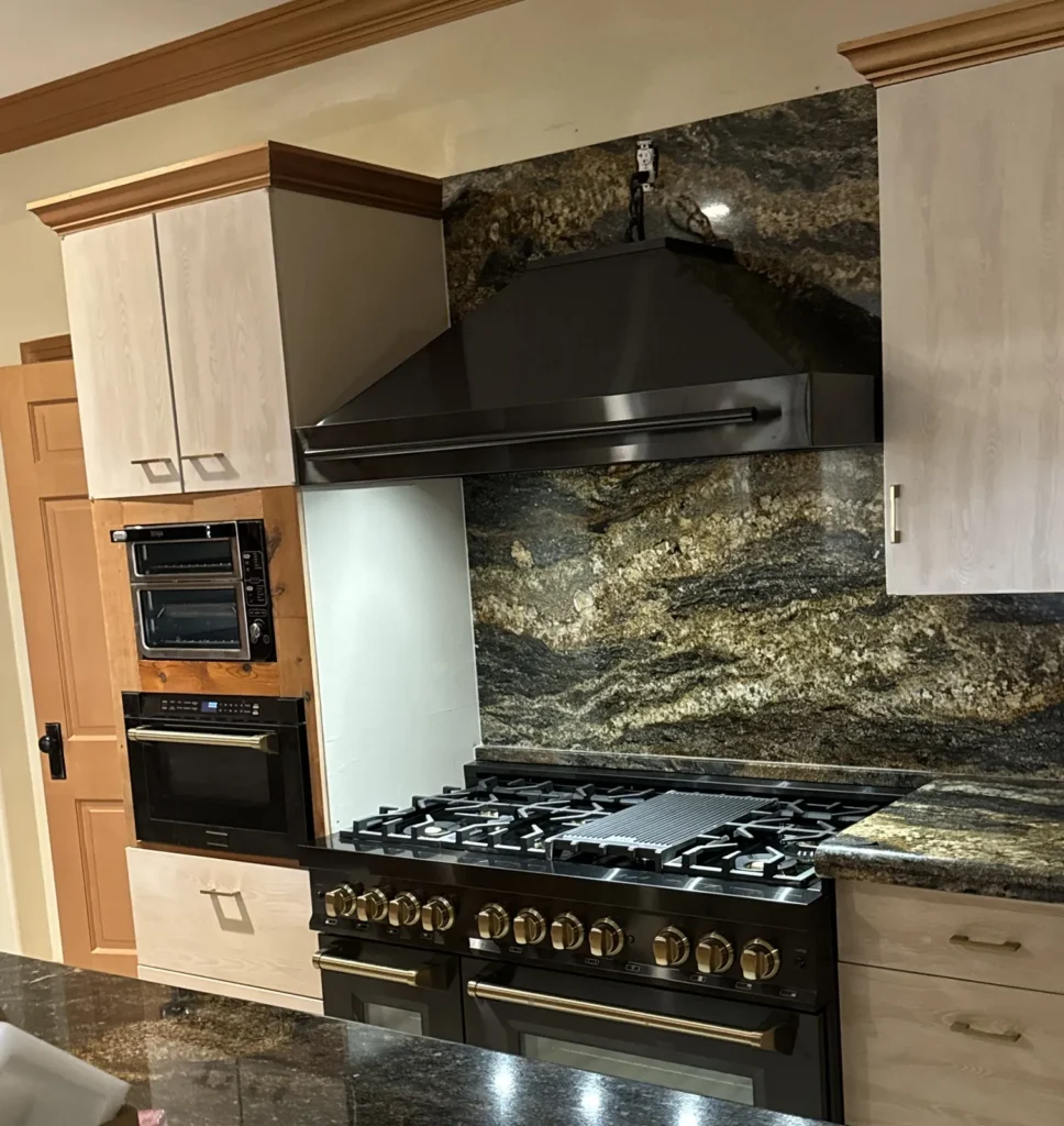 Exotic dark granite with gold veining on countertops and a full-height backsplash behind a pro-style range