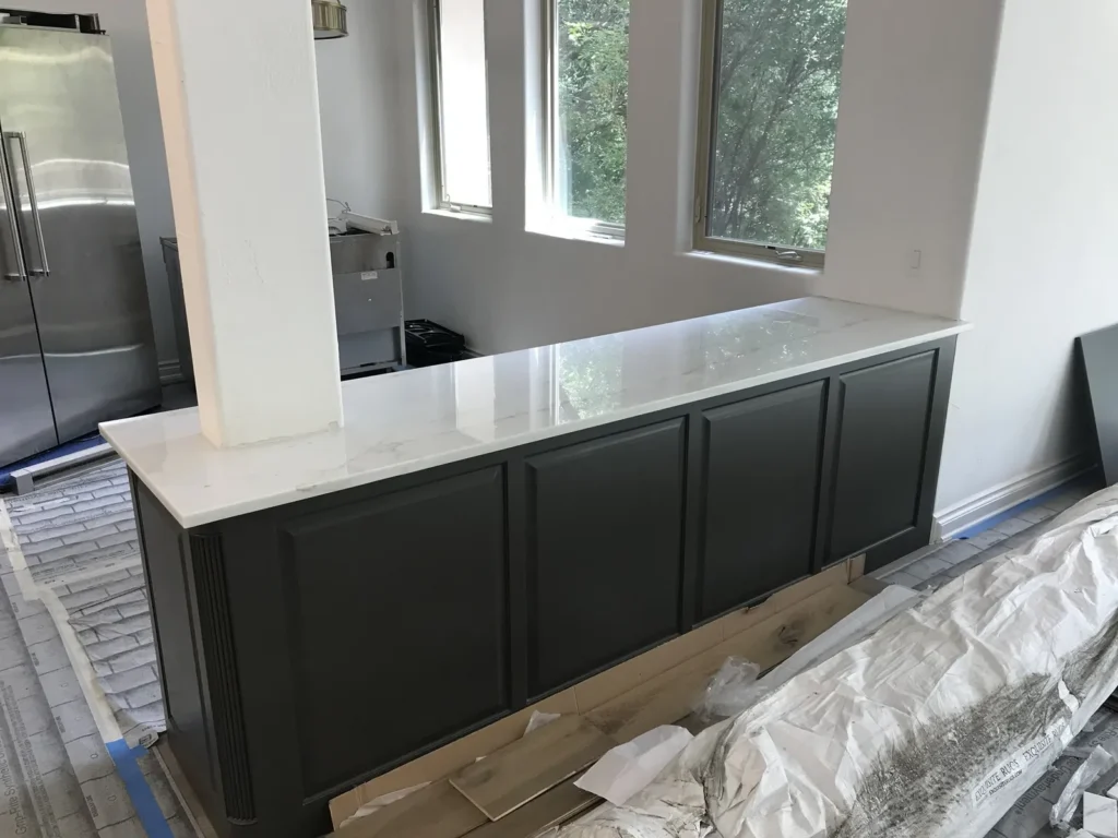 Polished white marble-look countertop on a dark painted peninsula cabinet wrapped around a column
