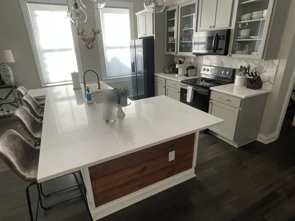 L-shaped white quartz island countertop with reclaimed wood island panel