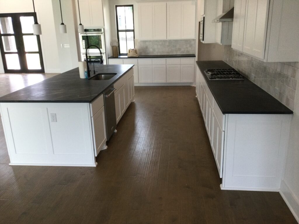 Black honed stone countertops on kitchen island and perimeter with white cabinets, Austin TX